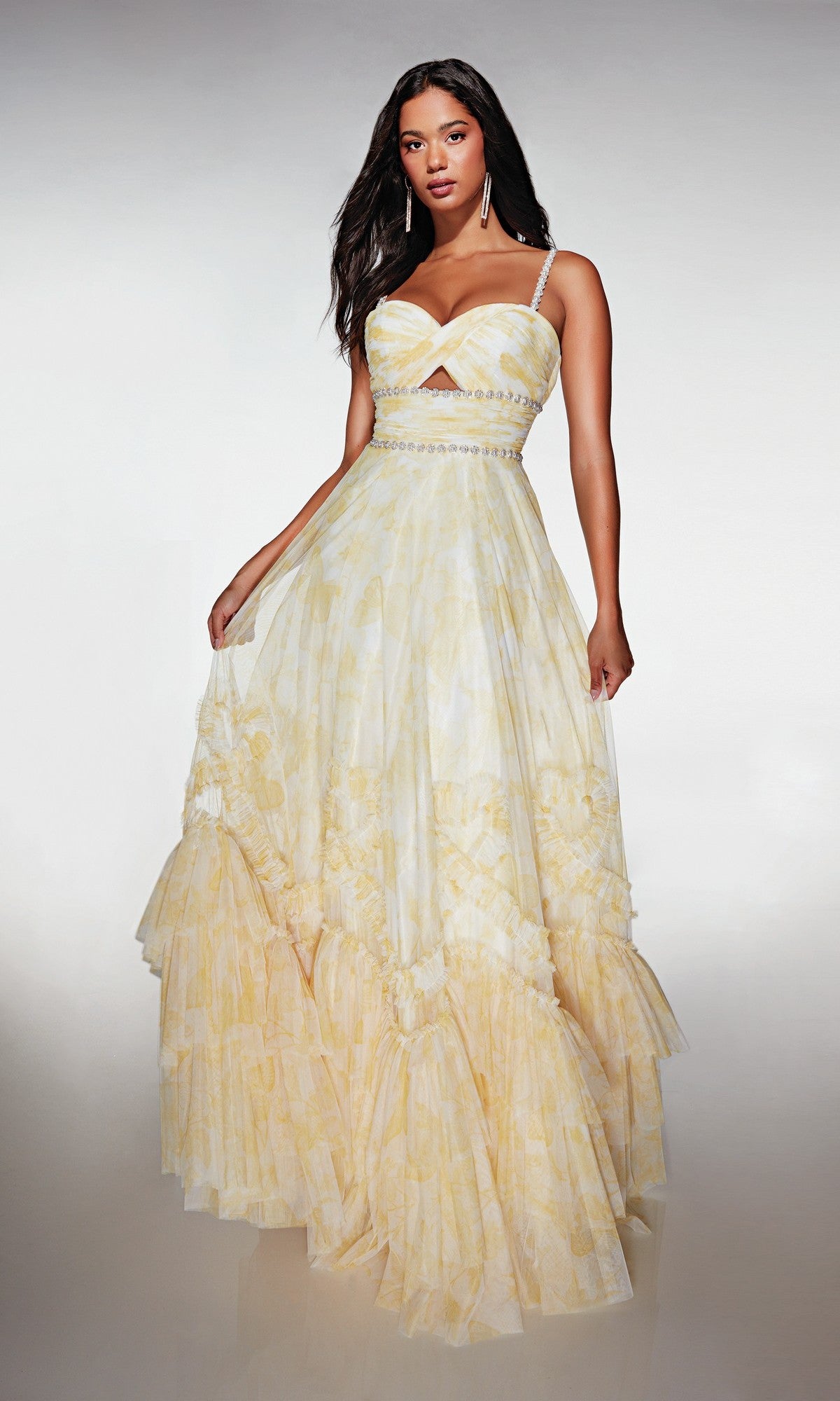 A woman wears the Alyce 62063 long formal dress in Buttercup, featuring a fitted bodice, spaghetti straps, and a ruffled hem, posing against a plain background.